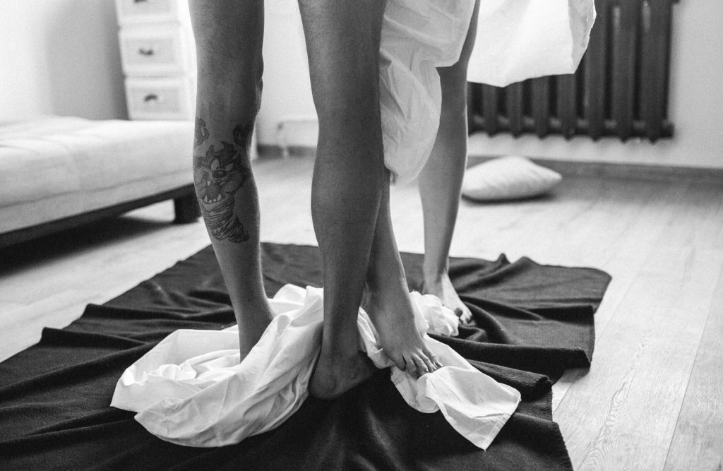Foto das pernas de casal abraçado sobre tecidos espalhados no chão.
