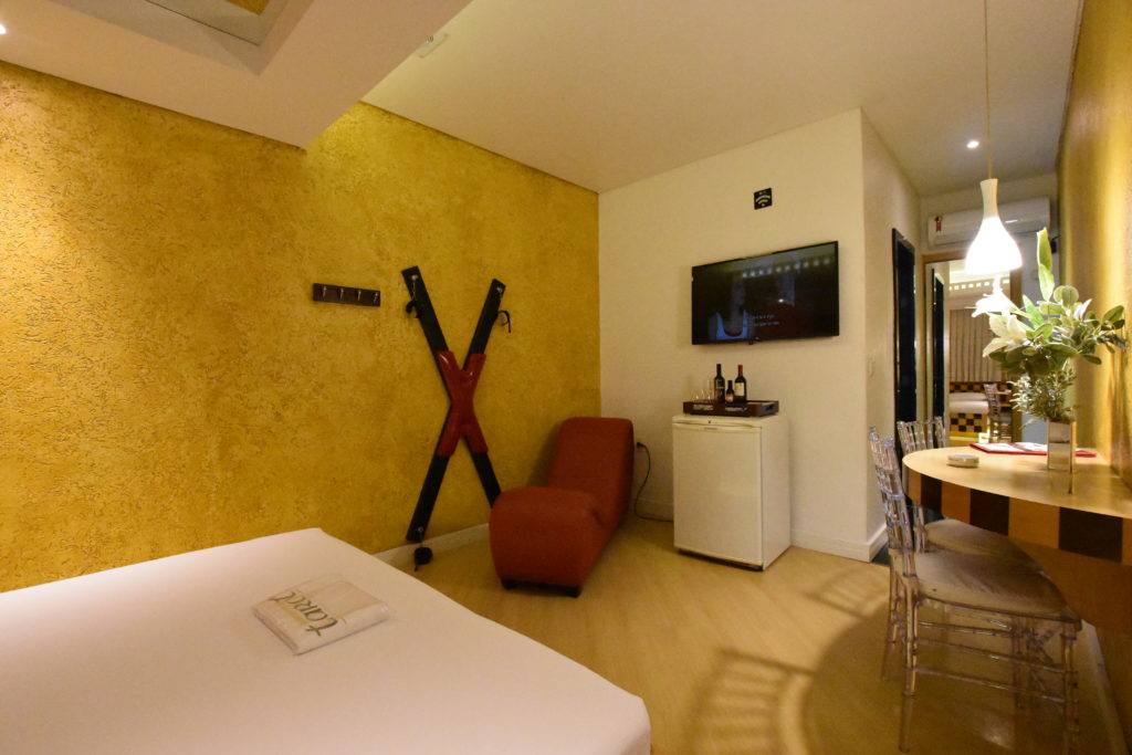 Foto de Xis Erótico instalado em parece amarela em suíte do Motel Tarot.
