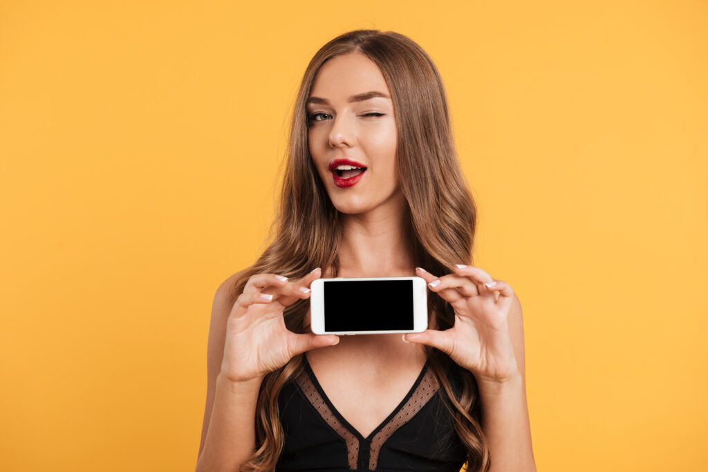 Mulher jovem, com celular na mão procurando aplicativo de namoro online